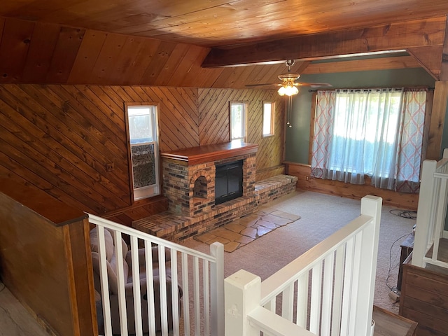 carpeted living room with lofted ceiling with beams, wood ceiling, a healthy amount of sunlight, and wood walls