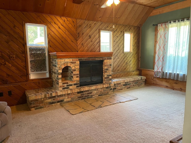 unfurnished living room featuring wood walls, wood ceiling, vaulted ceiling, carpet floors, and ceiling fan