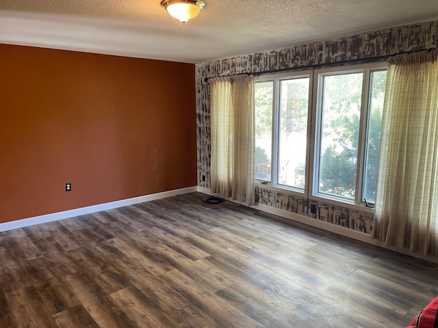 spare room with a textured ceiling, vaulted ceiling, and wood-type flooring