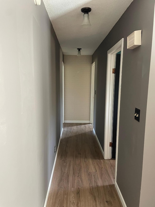 hall with wood-type flooring and a textured ceiling