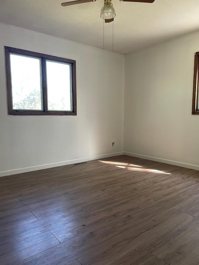 empty room with dark hardwood / wood-style floors, a textured ceiling, and ceiling fan