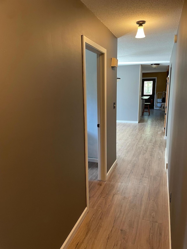 hall with a textured ceiling and light hardwood / wood-style floors