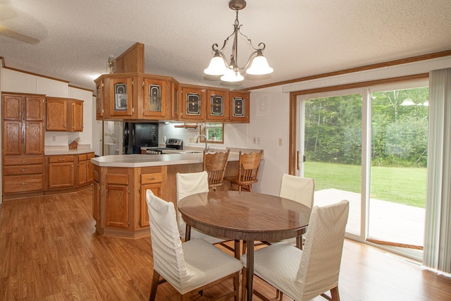 dining room featuring a notable chandelier, light wood-style flooring, a textured ceiling, and crown molding