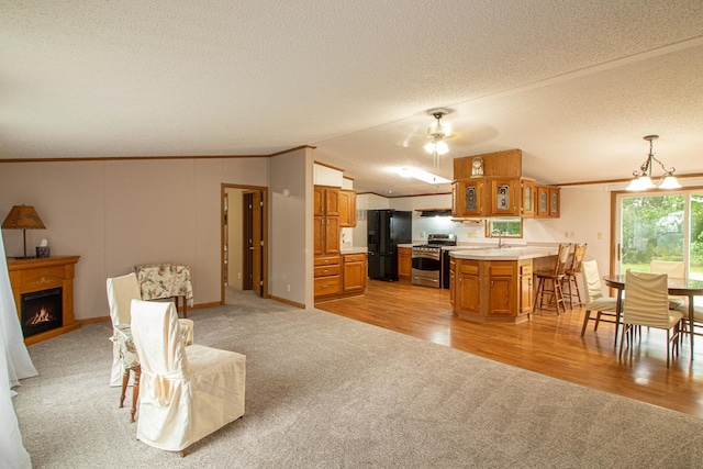 kitchen with brown cabinetry, open floor plan, light countertops, stainless steel range oven, and black fridge