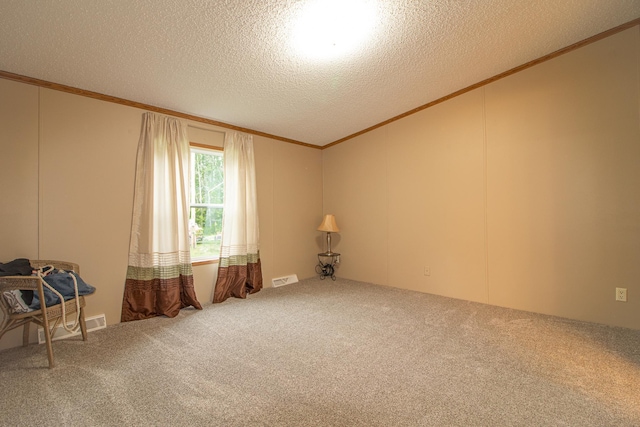 carpeted spare room featuring a textured ceiling, ornamental molding, and visible vents