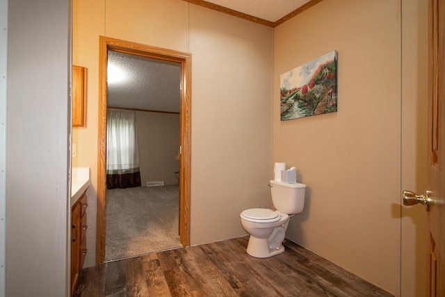 bathroom with crown molding, toilet, a textured ceiling, vanity, and wood finished floors