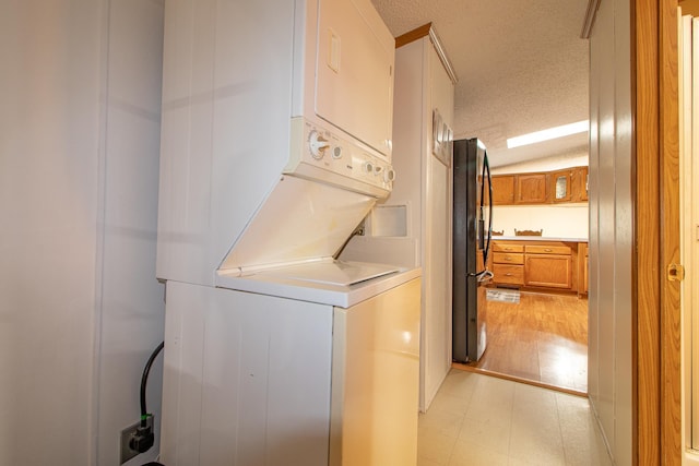 washroom with a textured ceiling, light floors, and stacked washer / dryer