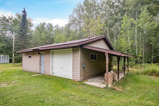 garage with driveway, a detached garage, and a view of trees