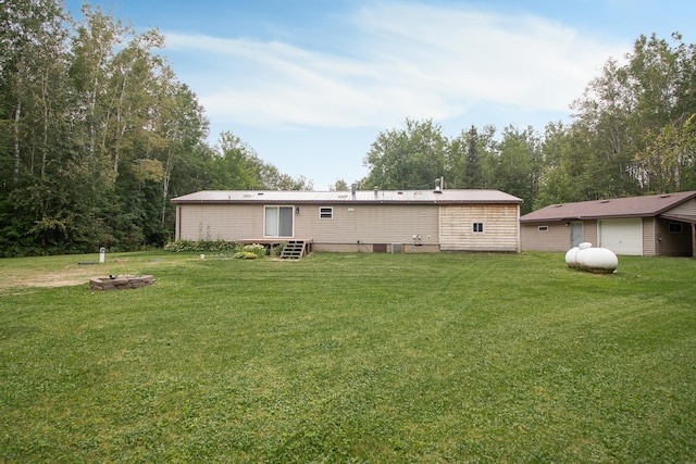 back of house featuring metal roof, a yard, and a detached garage