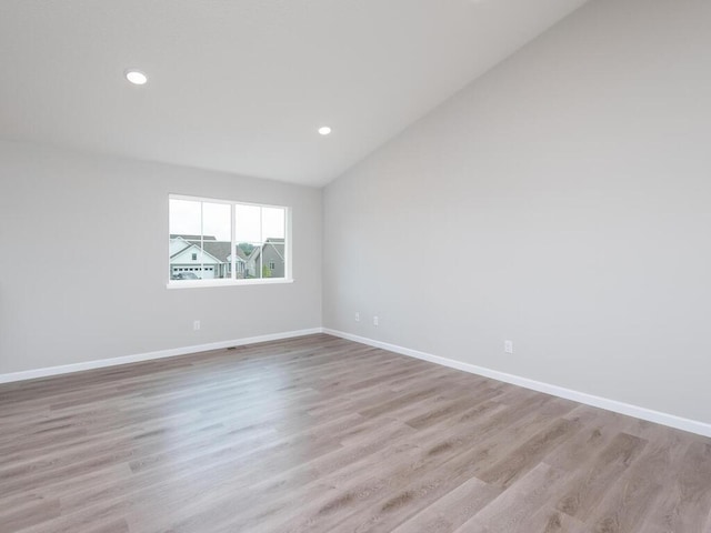 empty room featuring vaulted ceiling and light hardwood / wood-style flooring