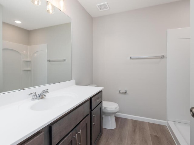 bathroom featuring hardwood / wood-style floors, vanity, toilet, and a shower