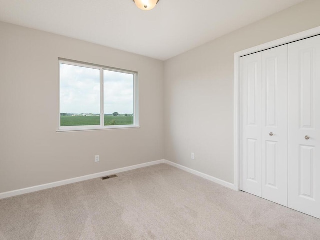 unfurnished bedroom with a closet and light colored carpet