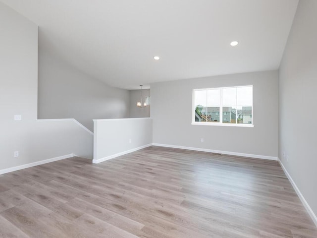 unfurnished room with light wood-type flooring and a notable chandelier