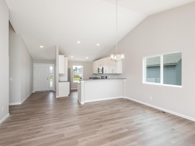 unfurnished living room with light hardwood / wood-style floors, lofted ceiling, and a chandelier