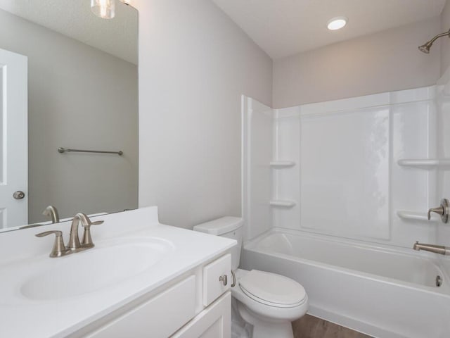 full bath with a textured ceiling, toilet, wood finished floors, vanity, and  shower combination