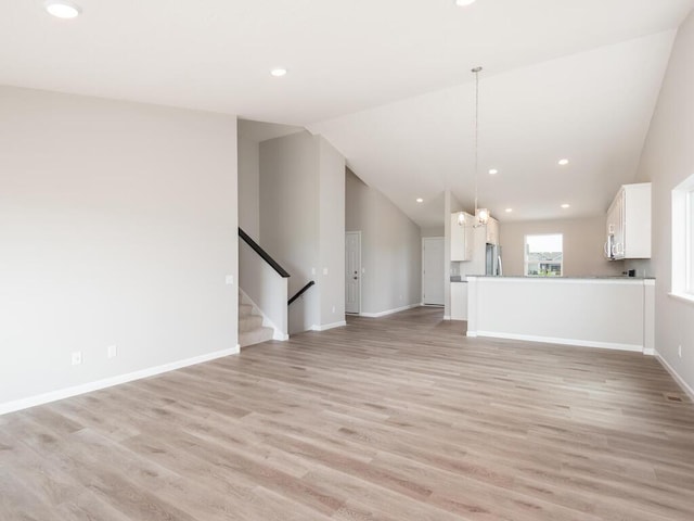 unfurnished living room with light hardwood / wood-style flooring and lofted ceiling