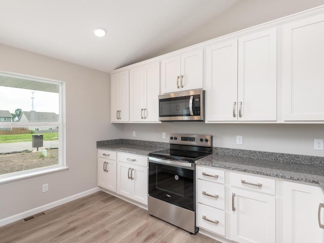 kitchen with visible vents, white cabinets, baseboards, light wood-style flooring, and stainless steel appliances