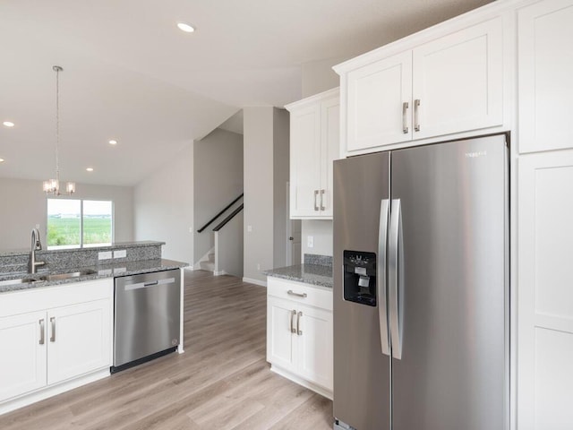 kitchen with sink, stainless steel appliances, dark stone counters, pendant lighting, and white cabinets