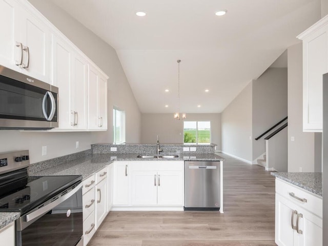 kitchen with kitchen peninsula, stainless steel appliances, sink, white cabinets, and lofted ceiling