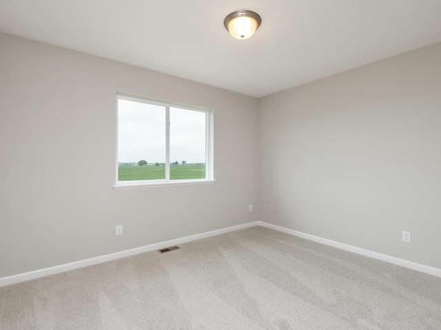 spare room with carpet flooring, visible vents, and baseboards