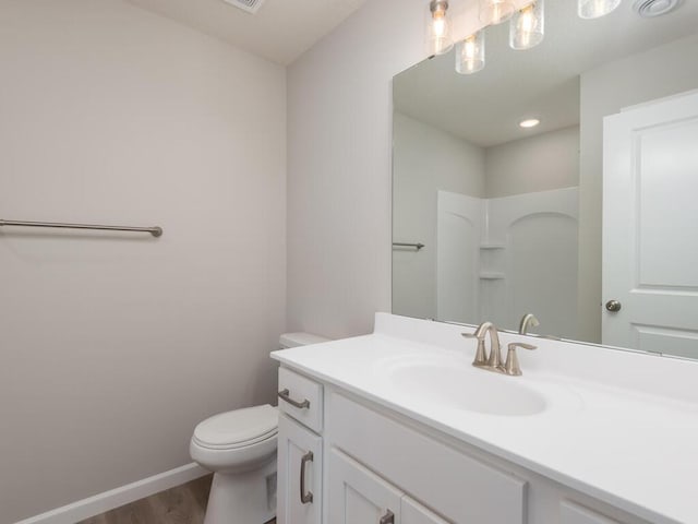 bathroom featuring hardwood / wood-style floors, vanity, toilet, and a shower