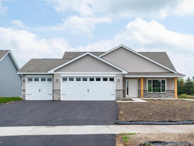 view of front of home with a shingled roof, stone siding, driveway, and an attached garage