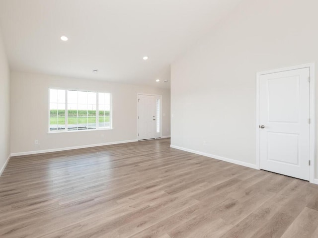 unfurnished room featuring light wood-type flooring, vaulted ceiling, baseboards, and recessed lighting