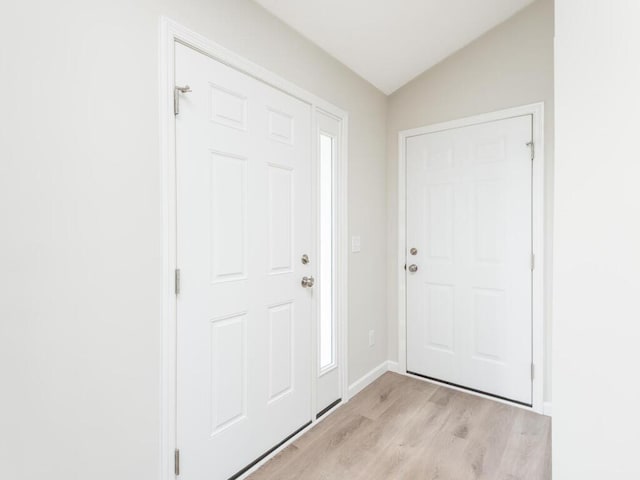 entrance foyer with lofted ceiling, light wood-type flooring, and baseboards