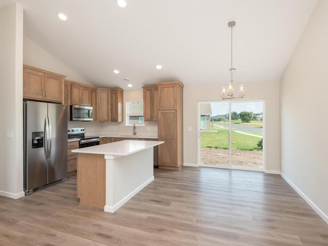 kitchen featuring a kitchen island, vaulted ceiling, light countertops, appliances with stainless steel finishes, and an inviting chandelier