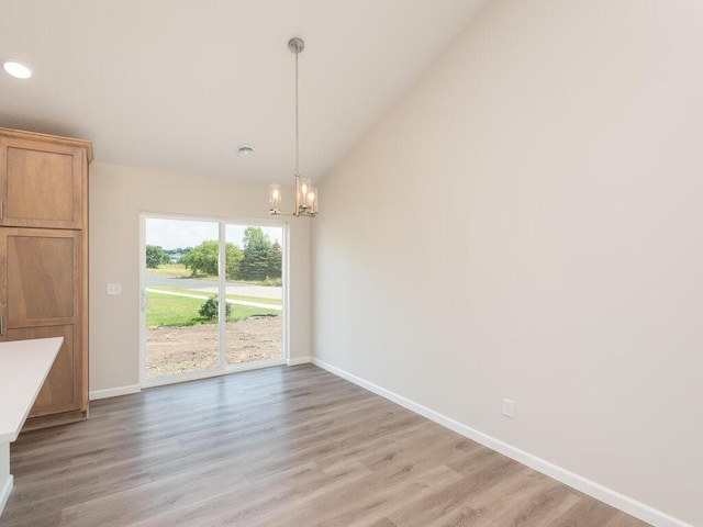 unfurnished dining area with lofted ceiling, recessed lighting, baseboards, light wood finished floors, and an inviting chandelier