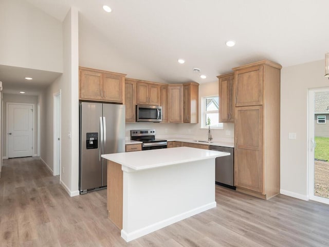 kitchen with a center island, stainless steel appliances, light countertops, vaulted ceiling, and a sink