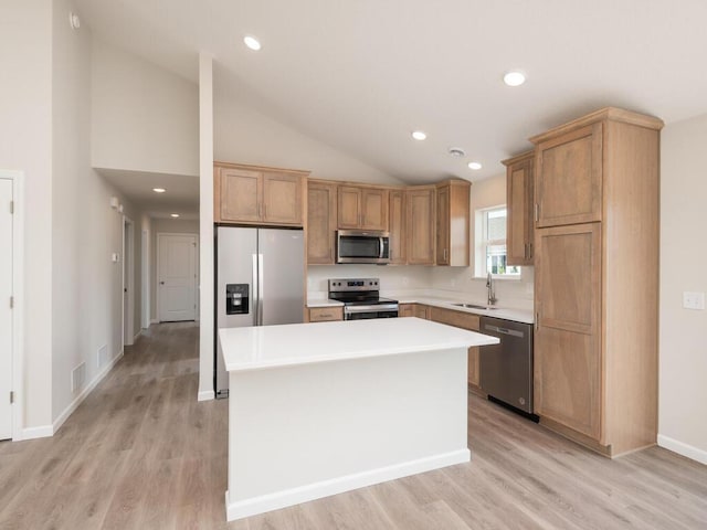 kitchen with a center island, stainless steel appliances, light countertops, light wood-type flooring, and a sink