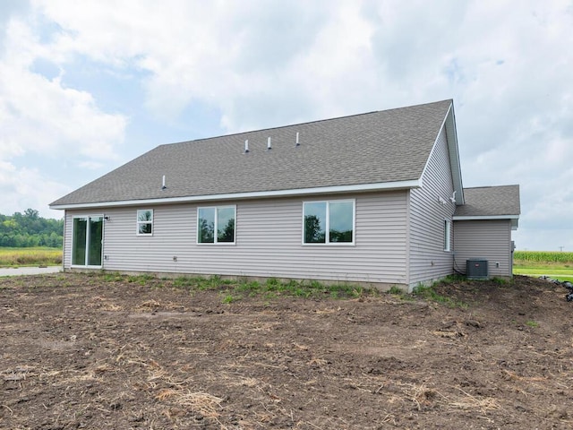 back of property with a shingled roof and cooling unit