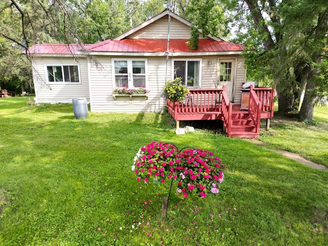 back of house featuring metal roof, a lawn, and a wooden deck