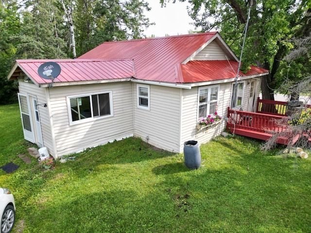 back of house with metal roof, a yard, and a wooden deck