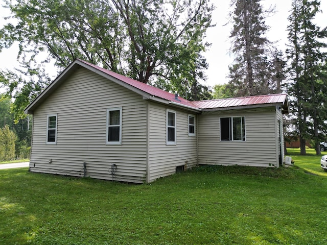 exterior space featuring metal roof and a lawn