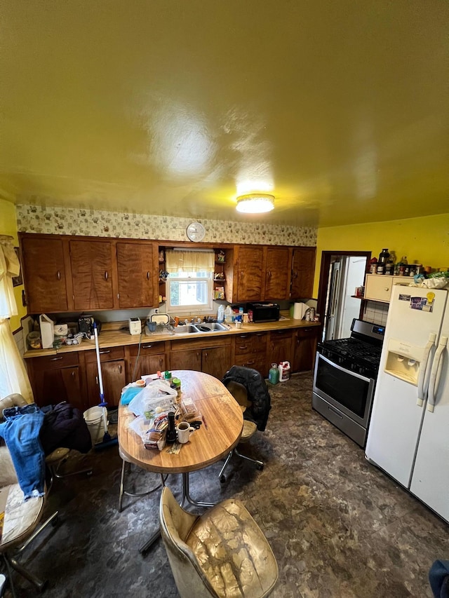 kitchen with gas range, white refrigerator with ice dispenser, and a sink