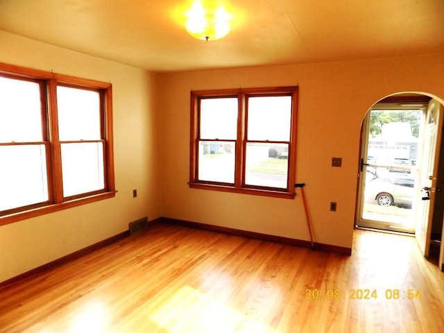 interior space with arched walkways, visible vents, light wood finished floors, and baseboards