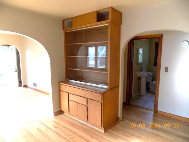 kitchen featuring visible vents, baseboards, open shelves, arched walkways, and light wood-style floors