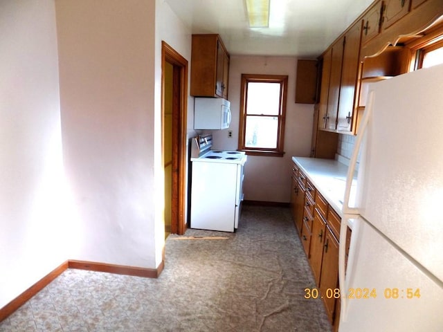 kitchen with washer / dryer, white appliances, and light carpet