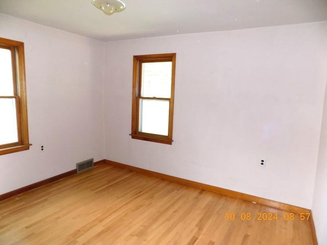 spare room with light wood-style floors, visible vents, and baseboards