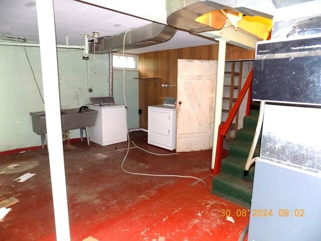 basement featuring washer / dryer, sink, and wooden walls