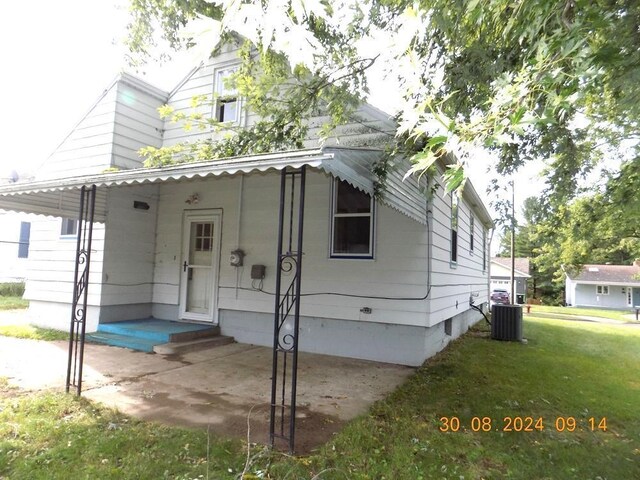 view of front of home with a porch, central AC unit, and a front yard