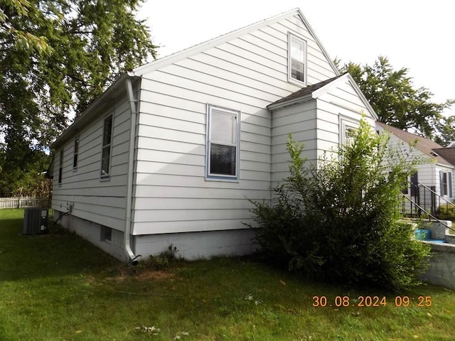 view of side of home with a yard and central AC