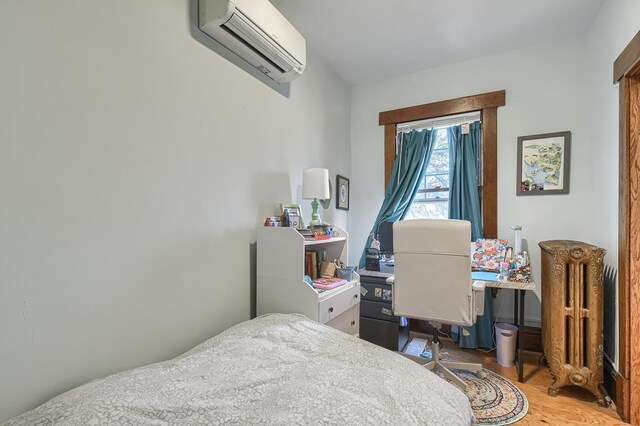 bedroom with a wall mounted AC and light wood-type flooring