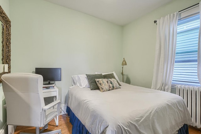 bedroom featuring radiator, multiple windows, and hardwood / wood-style floors