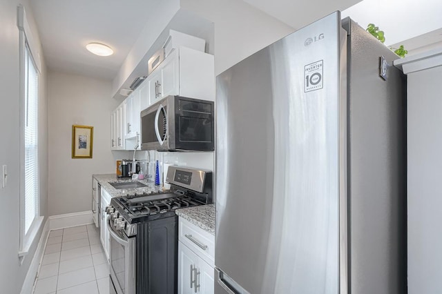 interior space with white cabinetry, a wealth of natural light, stainless steel appliances, and light stone countertops