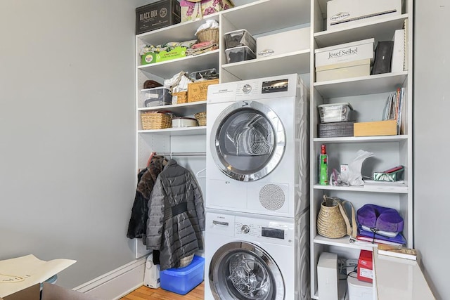 laundry area with stacked washing maching and dryer and light wood-type flooring