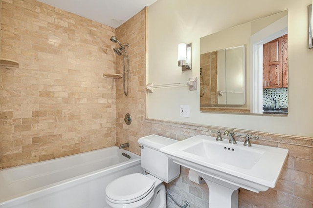 bathroom with tile walls, tiled shower / bath, and toilet