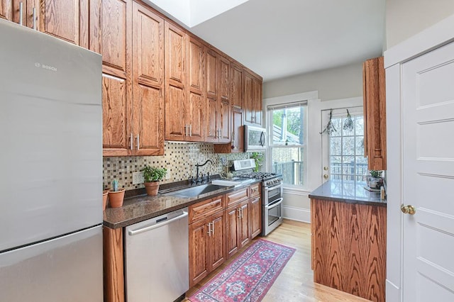 kitchen featuring appliances with stainless steel finishes, backsplash, sink, and light hardwood / wood-style flooring